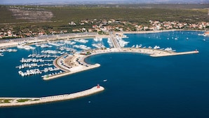 An aerial view of a marina with numerous boats docked, a lighthouse, and a coastal town in the background. - Sun-Kissed Sailing Adventure in Zadar, Croatia (Bibinje)