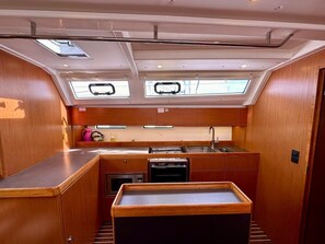 A compact kitchen with a central island, a sink, and a stove. There are skylights above the windows. - Sun-Kissed Sailing Adventure in Zadar, Croatia (Bibinje)