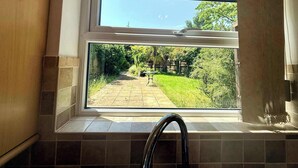 A kitchen with a window, a tiled backsplash, and a stainless steel faucet.