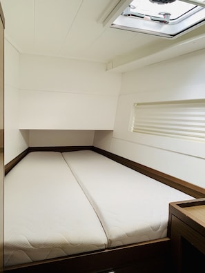 Ein kleines Zimmer mit einem Einzelbett, einem Dachfenster und einem Fenster.
