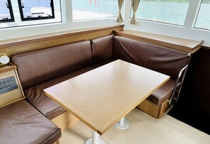 A corner seating area with a wooden table and brown leather bench. - Sun-Kissed Sailing Adventure in Isla de Mahe, Seychelles (Providence)