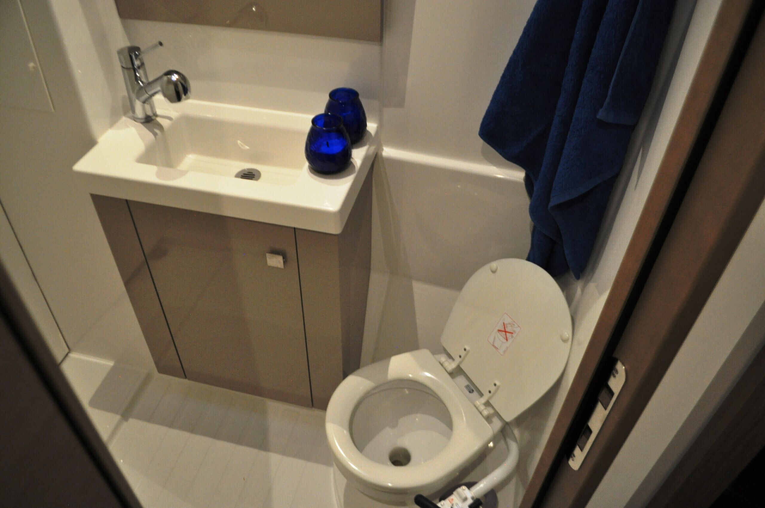 Ein Badezimmer mit Waschbecken, Toilette und einer blauen Kerze auf dem Waschbecken.