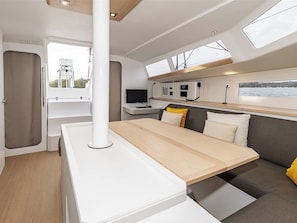 A modern interior with a dining table, sofa, and a window overlooking a body of water.