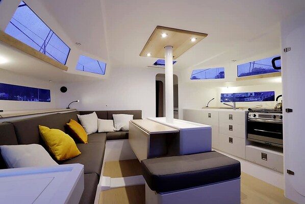 A modern interior with a sofa, ottoman, and a kitchenette area.