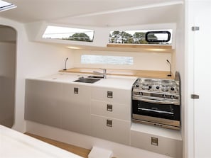 A compact kitchen with a sink, stove, and storage cabinets.