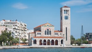 A church with a tall bell tower and a clock, surrounded by modern buildings and a waterfront. - Sun-Kissed Sailing Adventure in the Sporades Islands from Volos, Thessaly (Volos)