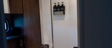 Une salle de bain moderne avec une porte de douche en verre, un lavabo blanc et un meuble en bois foncé.