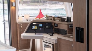 A boat's control station with a steering wheel, navigation screens, and a small refrigerator. - Sun-Kissed Sailing Adventure in Islas Baleares, Mallorca (Andratx)