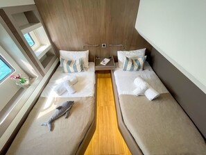 Une cabine avec deux lits, un mur lambrissé, une petite table avec un livre et une fenêtre donnant sur un paysage agréable.