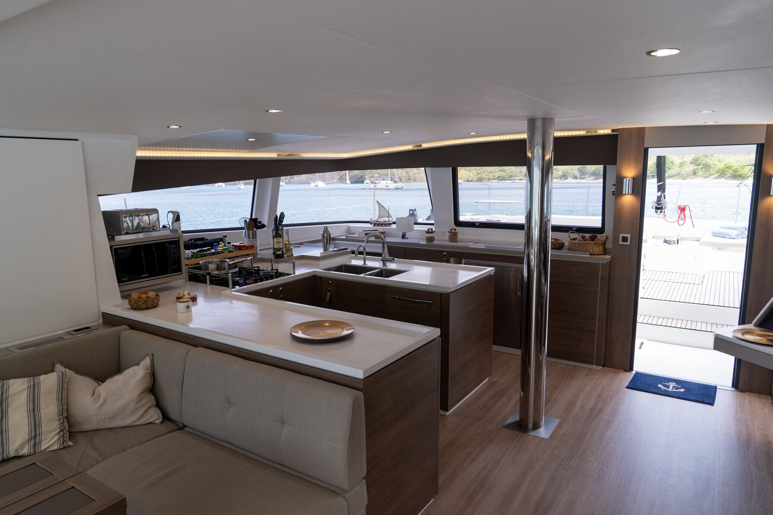 A modern kitchen with a central island, a dining area with a sofa, and a view of the water.