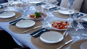 A dining table set with plates, cutlery, and glasses, with a view of the sea in the background. - Sun-Kissed Sailing Adventure in Islas Baleares, Mallorca (Andratx)