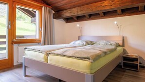 Une chambre à coucher avec un lit, une table de chevet, une fenêtre avec des rideaux et un plafond en bois.