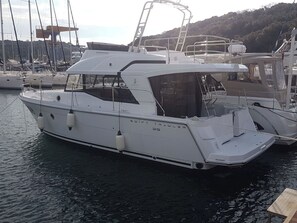 A white yacht named 'SWIFT TRAULER' docked at a marina with other boats and a mountainous backdrop. - Sun-Kissed Sailing Adventure in Istria, Croatia (Pula)