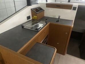 A kitchen with a built-in stove, a sink, and wooden cabinets. - Sun-Kissed Sailing Adventure in Istria, Croatia (Pula)