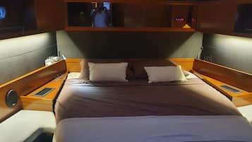 Un lit avec deux oreillers, une tête de lit et des tables de chevet en bois, sur lesquelles est posé un petit miroir.