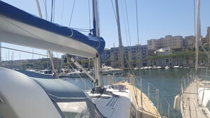 Un port de plaisance avec des bateaux amarrés, un ciel dégagé et des bâtiments en arrière-plan.