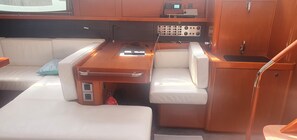 Un intérieur de bateau compact comprenant un panneau de commande, un espace salon et un petit évier.