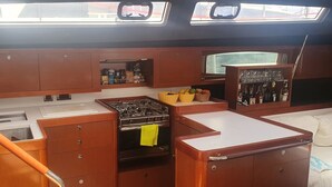 A compact kitchen with a stove, sink, and cabinets, and a small window above the sink. - Sun-Kissed Sailing Adventure in the Ionian Islands, Lefkada (Lefkada)