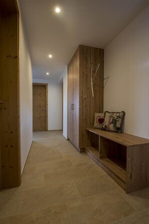 Ein Flur mit Holzboden, einer Bank mit Zierkissen und einem Holzkabinett.
