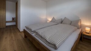 Et soveværelse med en træseng, hvide vægge og et sengebord med en lampe.