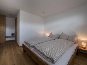 Ein Schlafzimmer mit einem hölzernen Bett, weißen Wänden und einem Nachttisch mit einer Lampe.