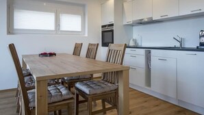 Et moderne køkken med hvide skabe, et træspisebord og en integreret ovn.