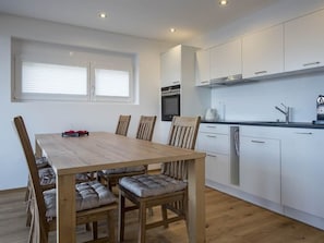 Eine moderne Küche mit weißen Schränken, einem Holztisch und einem eingebauten Backofen.
