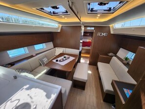 A yacht interior with a cozy seating area, a dining table, and a 'Home' sign on the wall. - Sun-Kissed Sailing Adventure in Sibenik, Croatia (Primošten)