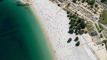 An aerial view of a beach with a parking lot and buildings.