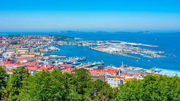 A coastal cityscape with a marina, buildings with red roofs, and a clear blue sky.