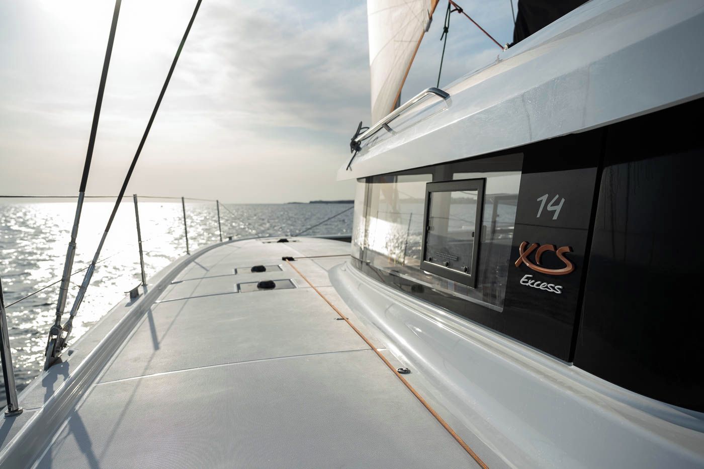 Ett däck på en segelbåt med fri sikt över vattnet, siffran ’14’ på sidan och logotypen ’XCS Excess’.