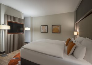 A hotel room with a large bed, a desk with a lamp, two framed artworks on the wall, and a modern design. - Clayton Hotel Tiergarten Berlin (Berlin)