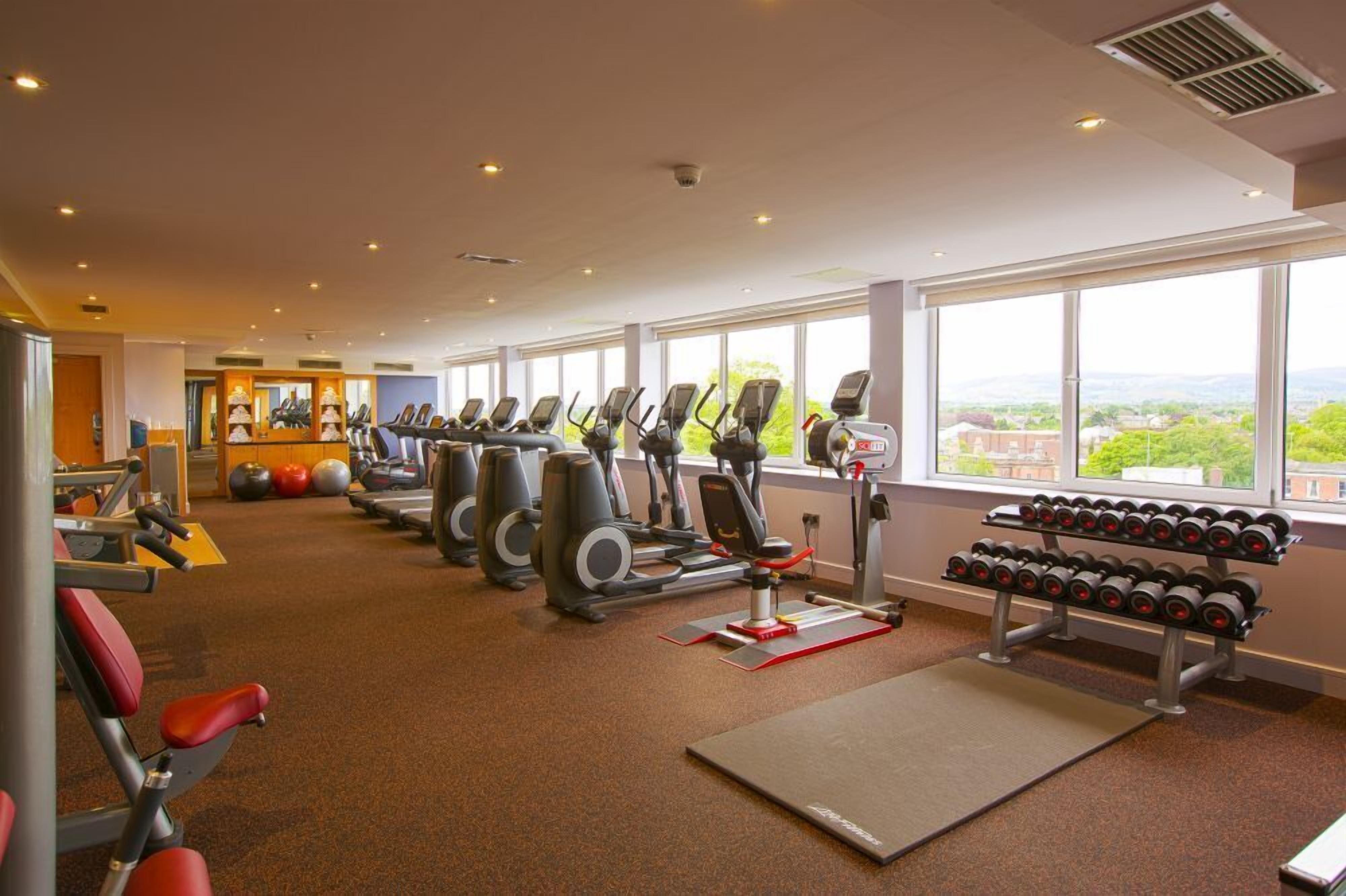 A gym with cardio machines, weight benches, and dumbbells.