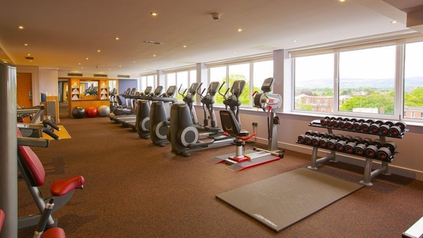 A gym with cardio machines, weight benches, and dumbbells.