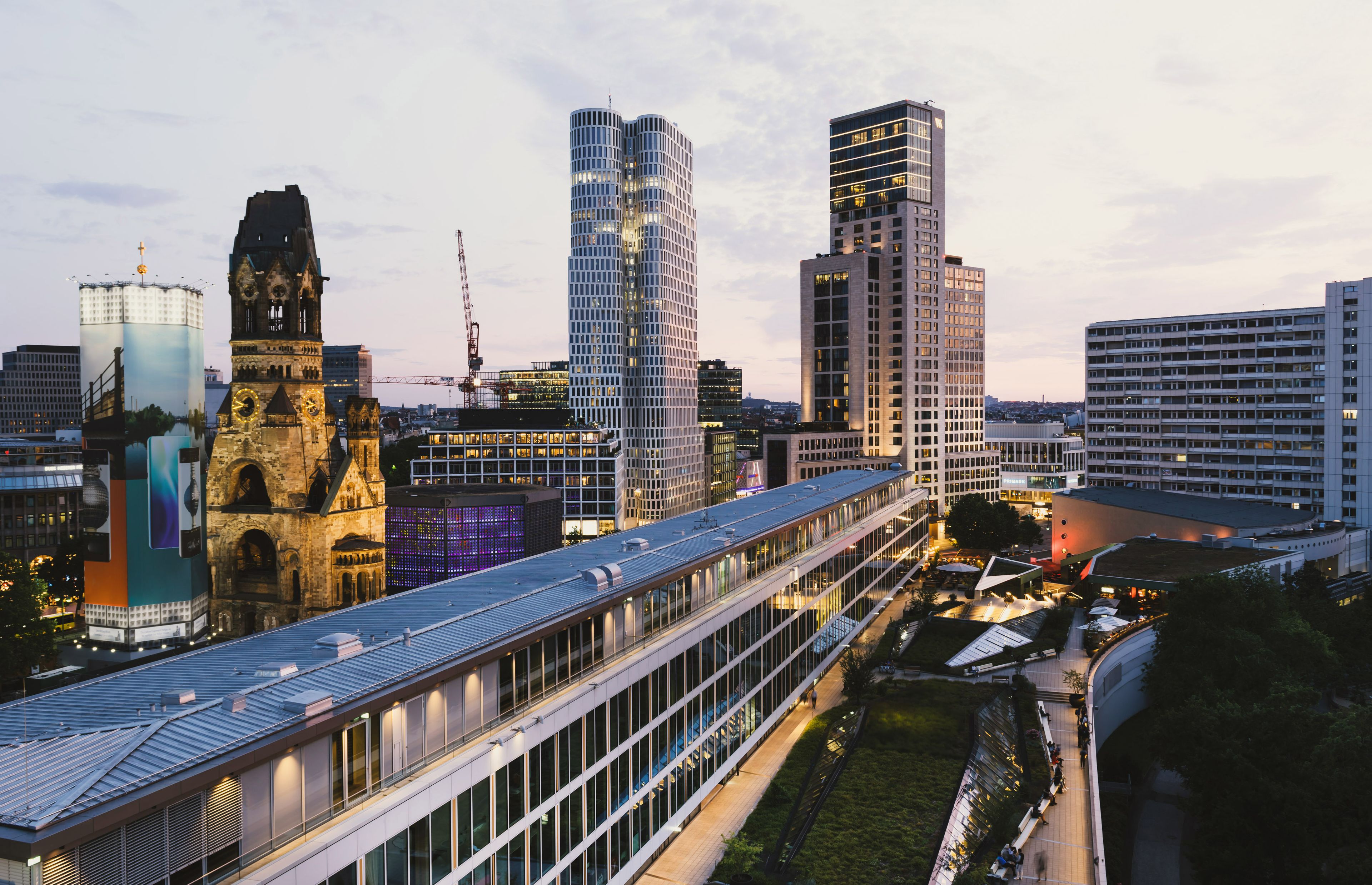 A modern cityscape with a mix of historical and contemporary architecture, including a prominent clock tower and a high-rise building with a unique facade.