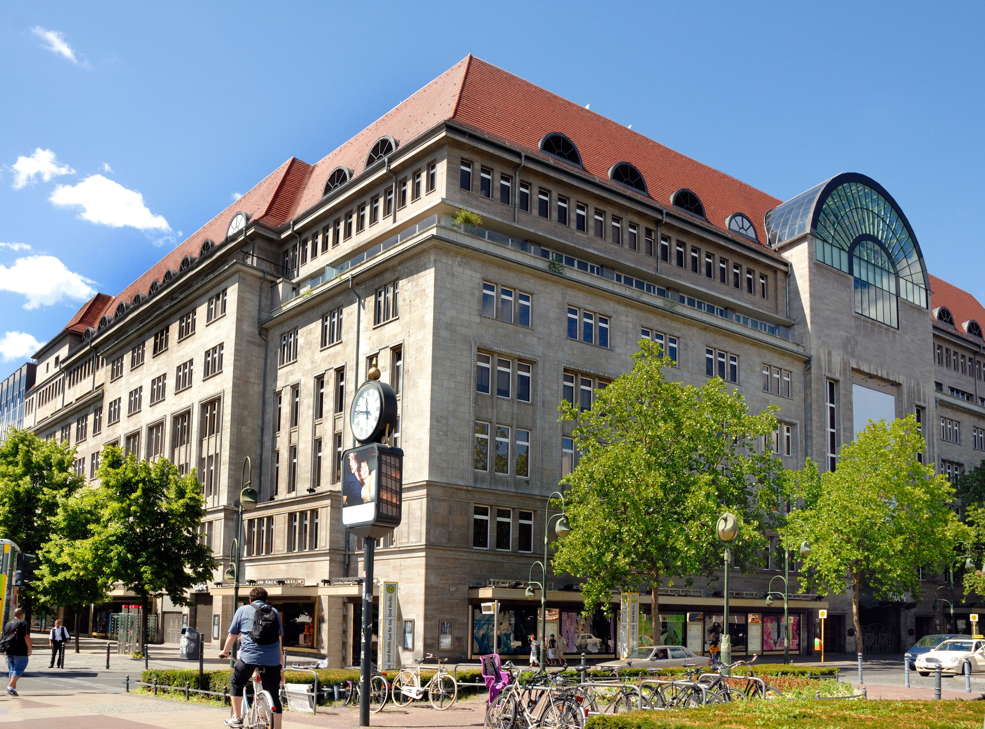 A historic building with a clock tower, large windows, and a red roof.