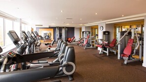 Un gimnasio con cintas de correr, máquinas de pesas y un reloj de pared.