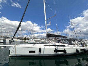 Ein Yachthafen mit mehreren Segelbooten, darunter ein weißes Boot mit der Aufschrift 'BENETEAU'.