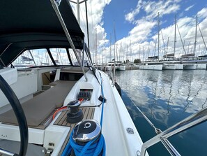 A boat deck with a steering wheel, control panel, and a blue rope coiled on the edge. - Sun-Kissed Sailing Adventure in Islas Sarónicas (Alimos)