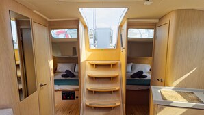 A compact RV interior with two beds, a central storage unit, and a small seating area. - Sun-Kissed Sailing Adventure in Islas Sarónicas (Alimos)
