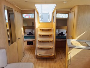 Ein kompaktes Wohnmobil-Interieur mit zwei Betten, einer zentralen Stauraum-Einheit und einer kleinen Sitzecke.