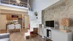 Un interior moderno con zona de comedor, cocina y una escalera que sube a un nivel superior.