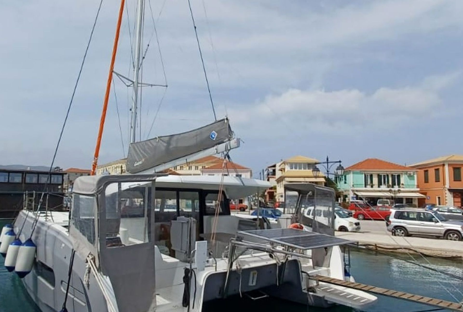 A marina with boats docked, a covered area, and buildings in the background.