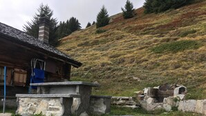 A rustic cabin with a stone bench, wooden deck, and a stone fireplace. - Alphütte Bielerchäller Appartement/Fewo, Dusche oder Bad, WC, 1 Schlafraum by Interhome (Fiesch)