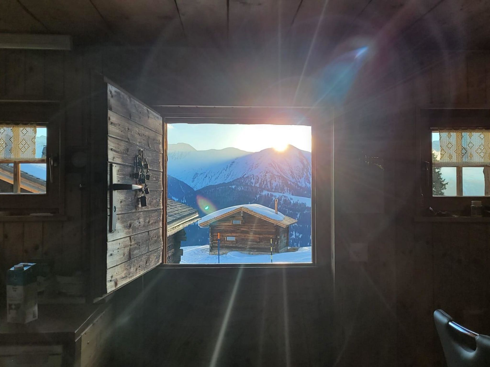 Una cabana amb un gran finestral que mostra un paisatge de muntanya nevada i façana de fusta.