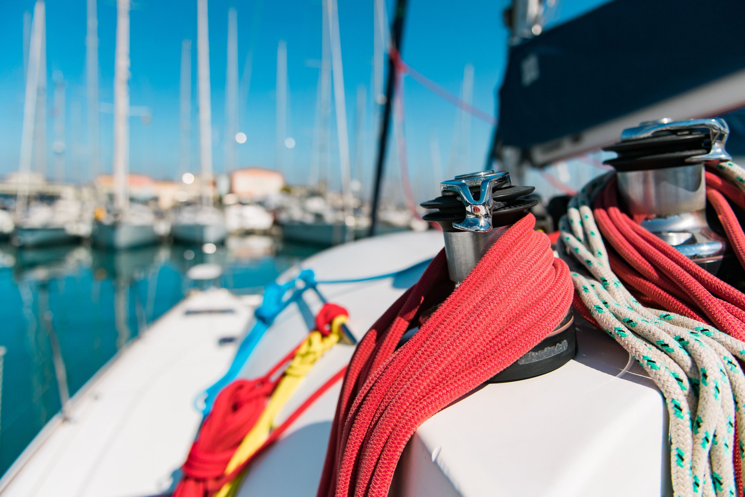 A sailboat's rigging with multiple ropes and a cleat.