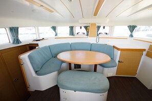 A compact boat interior with a round table, cushioned seating, and a small cabinet. - Sun-Kissed Sailing Adventure in the Ionian Islands, Lefkada (Lefkada)