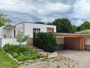 A modern house with a white exterior, a covered garage, and a well-maintained garden with various plants and a gravel driveway. - Villa Sunrise Labin, Istria - a smile every day (Nedešćina)