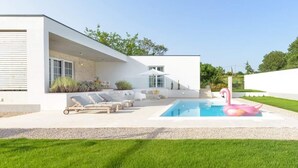 Ein modernes Haus mit Schwimmbad, Sitzgelegenheiten im Freien und einem rosa Flamingo-Schwimmpfad.