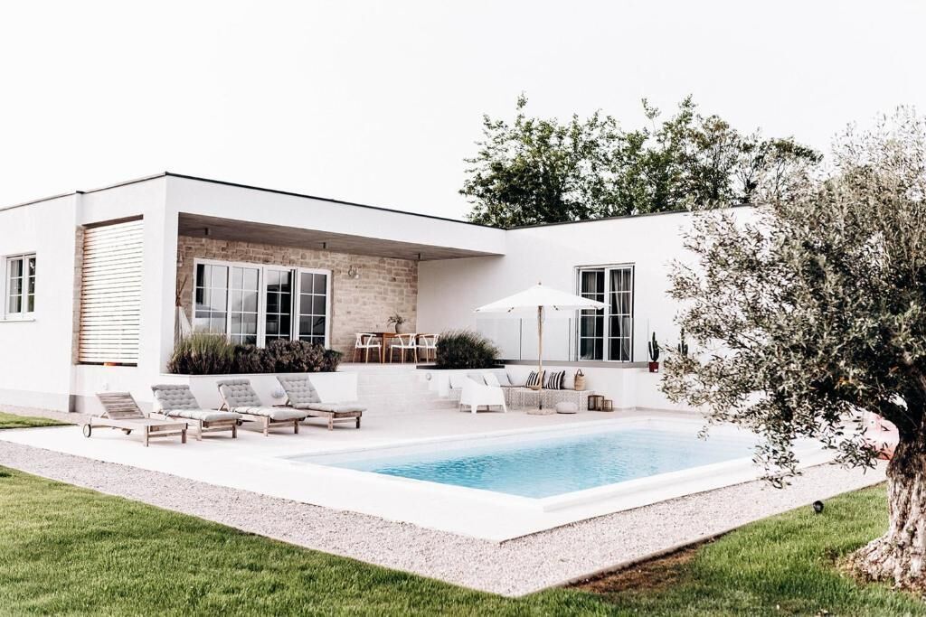 A modern house with a swimming pool, outdoor seating, and a patio area.